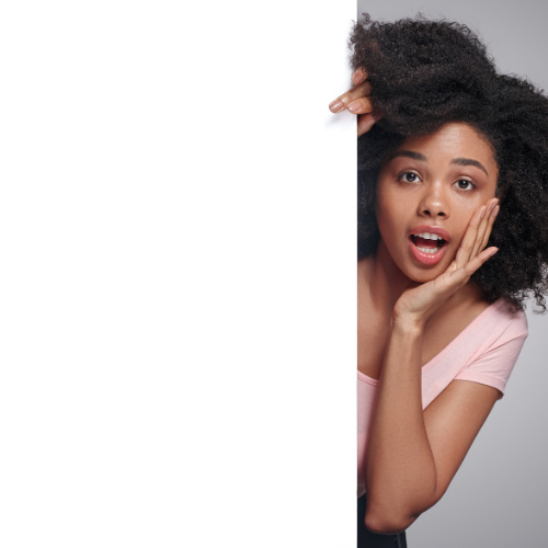 Black woman standing behind a white wall whispering